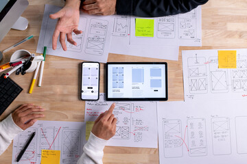UX UI designers discussing and brainstorming on wireframes for a website and mobile app prototype,...