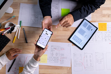UX UI designers discussing and brainstorming on wireframes for a website and mobile app prototype,...