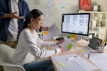 UX UI designers discussing and brainstorming on wireframes for a website and mobile app prototype,...
