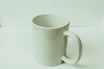 Plain white mug on a white table, photo suitable for mockup example.