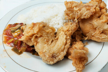 Rice mixed with flour fried chicken on a white plate on the table