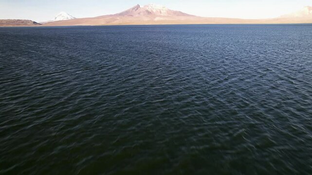 Aerial Drone Footage Captures Stunning Views Of Snow-Capped Mountains In Lauca National Park, Chile. The Camera Glides Over Lago Chungara, Revealing Deep Blue Waters On A Sunny Autumn Day.