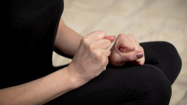 Woman nervously clenching fists tightly causing pain. Female tightly balling fists in anxiety feeling pain. Lady nervously tightening fists hands in agony