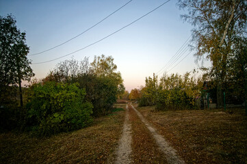 Fototapeta premium Dirt road through the village in autumn