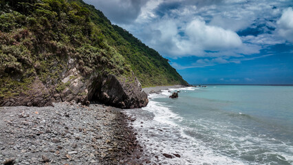 Obraz premium Coastal view of Taiwan showcasing rock formations and calm waters under a cloudy sky