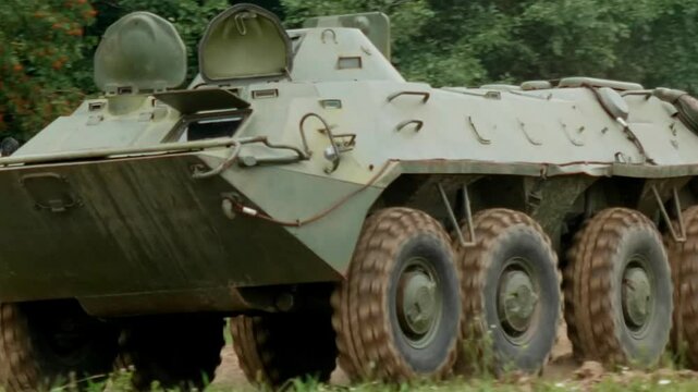 The armored personnel carrier moves across a military proving ground, demonstrating its amphibious capabilities and robust design, intended for transporting personnel and providing fire support.