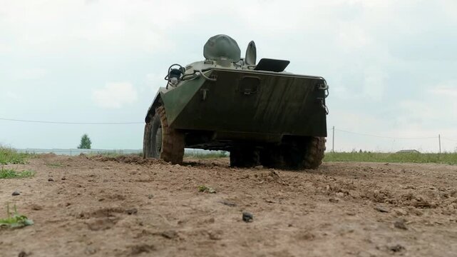The armored personnel carrier moves across a military proving ground, demonstrating its amphibious capabilities and robust design, intended for transporting personnel and providing fire support.