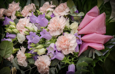 Flower arrangement. A beautiful memorial bouquet at the cemetery. Memorial flowers include pink carnations and blue bellflowers. Dark vignetting.