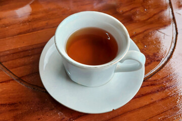 Hot tea in a white glass on a wooden table ready to drink