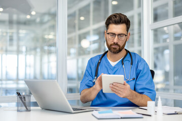 Doctor using tablet and laptop in modern office. Stethoscope around neck, focused on healthcare...