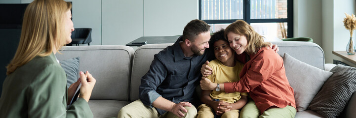 Family enjoying time together on couch with child. Everyone looks happy and comfortable while...
