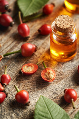 Closeup of rosehip berries and seeds with a bottle of rose hip oil in the background