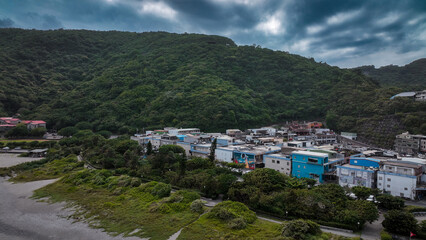 View of Nanfangao in Taiwan with lush hills and coastal buildings under an overcast sky