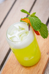 High angle shot, Midori Sour cocktail with slice dried lemon and mint leaves on wooden planks in front of a pool