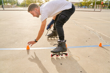 Man adjusting cones while rollerblading in an outdoor park