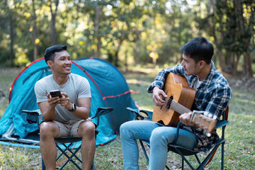 Two Friends Enjoying a Relaxing Camping Trip with Music and Nature in a Scenic Forest Setting