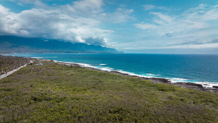 A scenic view of Taiwan coastline with lush greenery and mountains under a blue sky