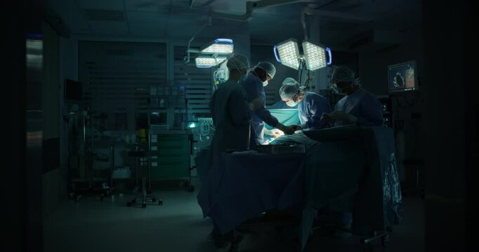 Surgeons and Assistants Perform Delicate Surgical Work. Specialists Staying Calm, Monitoring Vital Readouts On the Screens, Using Advanced Forceps, Graspers and Dissectors to Work on Tissue