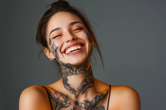 Young woman with face and neck tattoos laughs happily. Studio shot against neutral background. Stylish and expressive. Suitable for beauty and body art content. Great for social media marketing.