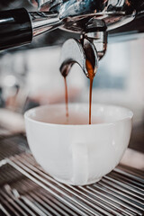 A close-up shot of rich espresso flowing from an espresso machine into a white cup, highlighting the brewing process and the texture of the coffee. Perfect for coffee-related themes.