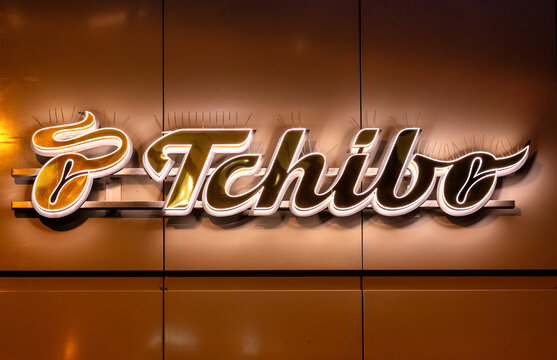 Darmstadt, Germany, 20.11.2024: Illuminated Tchibo lettering, logo, emblem on a facade at night. Tchibo is a German coffee house chain.