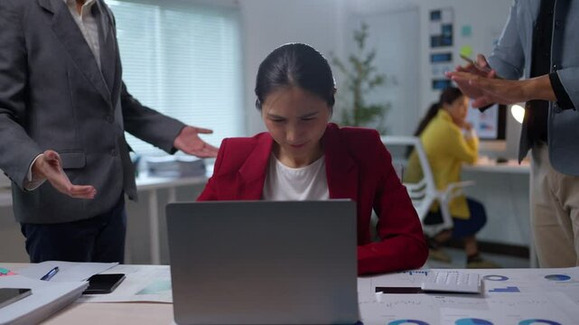 Businesswoman receiving criticism from her manager while working at her desk, showcasing workplace stress and tension
