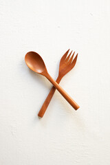 Cross-arranged solid wooden spoon and fork isolated on white background