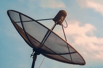 Old satellite dish against sunset sky. Broadcasting telecommunication technology.