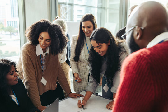 Diverse group of professionals engaged in a brainstorming meeting, collaborating with enthusiasm and teamwork