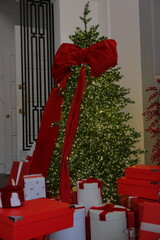 large Christmas tree with red bow and toys. New Year's decor, gift box on Christmas Eve. holidays, traditions. Garland decoration