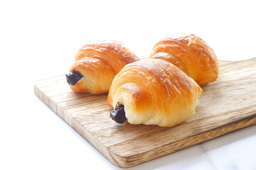 朝食のテーブルで、サービングボードでサーブされる、チョコレートが入ったクロワッサン
