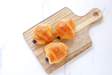 朝食のテーブルで、サービングボードでサーブされる、チョコレートが入ったクロワッサン
