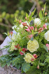 A beautiful and delicate green-toned memory bouquet. Funeral flowers of white roses, greenish carnations and pink Inca lilies.