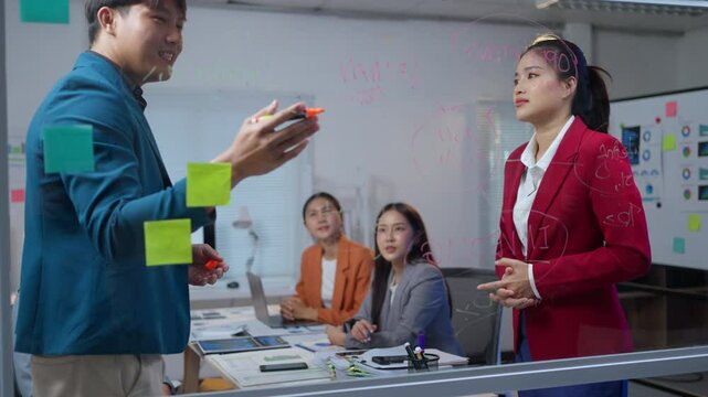 Businessman explaining strategy on a glassboard while collaborating with a colleague in a professional office setting
