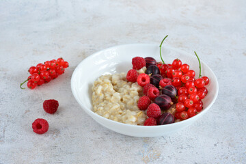 a bowl of boiled oatmeal with raspberries and red currant