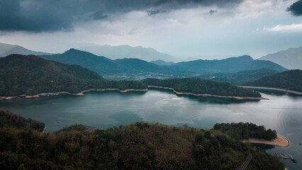 Naklejka premium Majestic view of Sun Moon Lake in Taiwan amidst dramatic clouds and serene waters