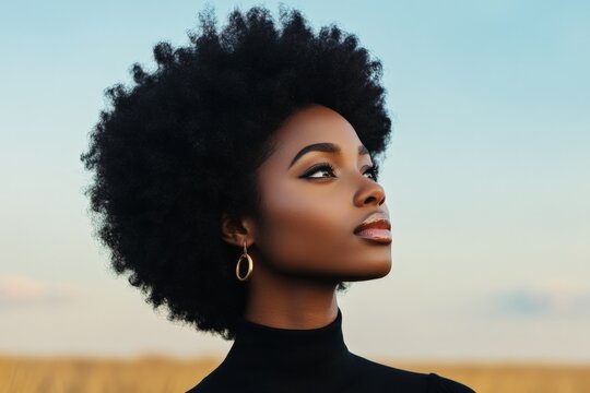 A striking profile of an elegant woman with an afro hairstyle gazing upwards against a serene outdoor backdrop, symbolizing strength and hope.