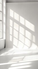 Fototapeta premium Sunlight casts geometric shadows through a window onto a pristine white wall, creating a mesmerizing interplay of light and shadow in a minimalist interior space.