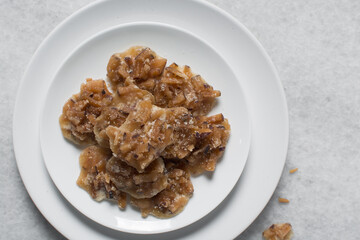 Overhead view of nigerian coconut candy on a white plate, top view of candied coconuts discs, flatlay of bukayo candy or coconut drops