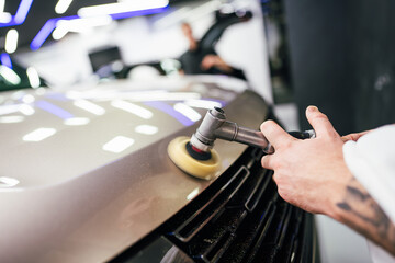 Professional vehicle polishing and detailing service in a modern car workshop. Brightly lit workspace with large led lights. High quality car valeting concept.