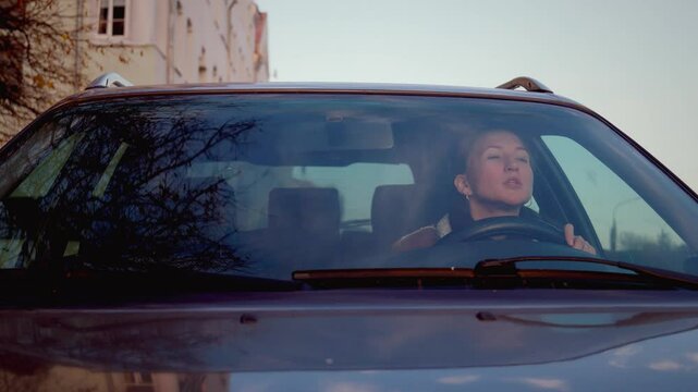 Woman expresses variety of emotions while driving, showing feelings of happiness, sadness, anger, and frustration while riding in car. Swears and shouts at other drivers and people.