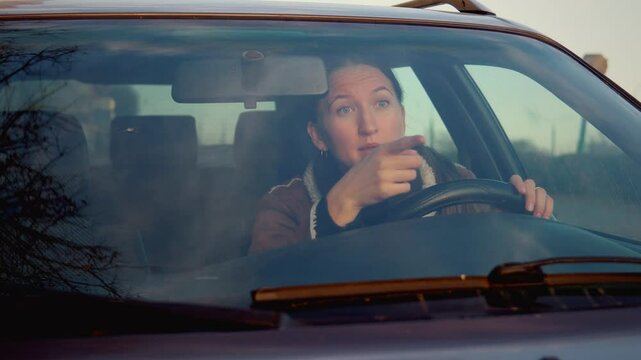 Woman expresses variety of emotions while driving, showing feelings of happiness, sadness, anger, and frustration while riding in car. Swears and shouts at other drivers and people.