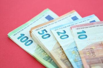 Big amount of one hundred, twenty, ten and fifty euro money bills on red background