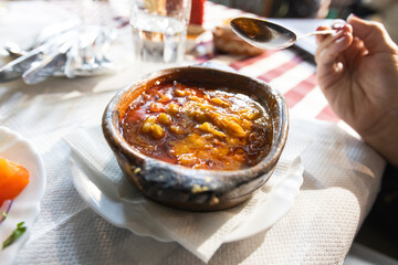 Close-up of a traditional Macedonian dish, Tavče Gravče, baked beans, served in a clay pot at restaurant.