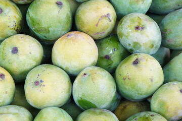 A pile of green mangoes, showcasing their vibrant color and smooth skin.