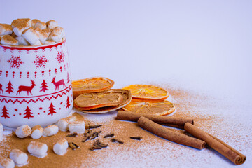 A pile of orange slices and cinnamon sticks on a white background. The oranges are cut in half and the cinnamon sticks are whole. Concept of warmth and comfort