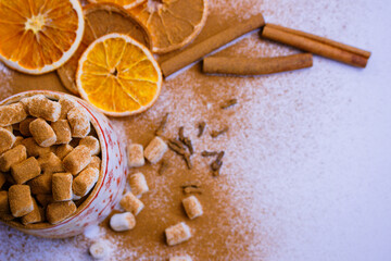 A pile of orange slices and cinnamon sticks on a white background. The oranges are cut in half and the cinnamon sticks are whole. Concept of warmth and comfort