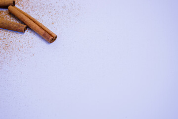 A pile of orange slices and cinnamon sticks on a white background. The oranges are cut in half and the cinnamon sticks are whole. Concept of warmth and comfort