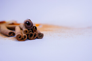 A pile of orange slices and cinnamon sticks on a white background. The oranges are cut in half and the cinnamon sticks are whole. Concept of warmth and comfort