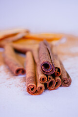 A pile of orange slices and cinnamon sticks on a white background. The oranges are cut in half and the cinnamon sticks are whole. Concept of warmth and comfort